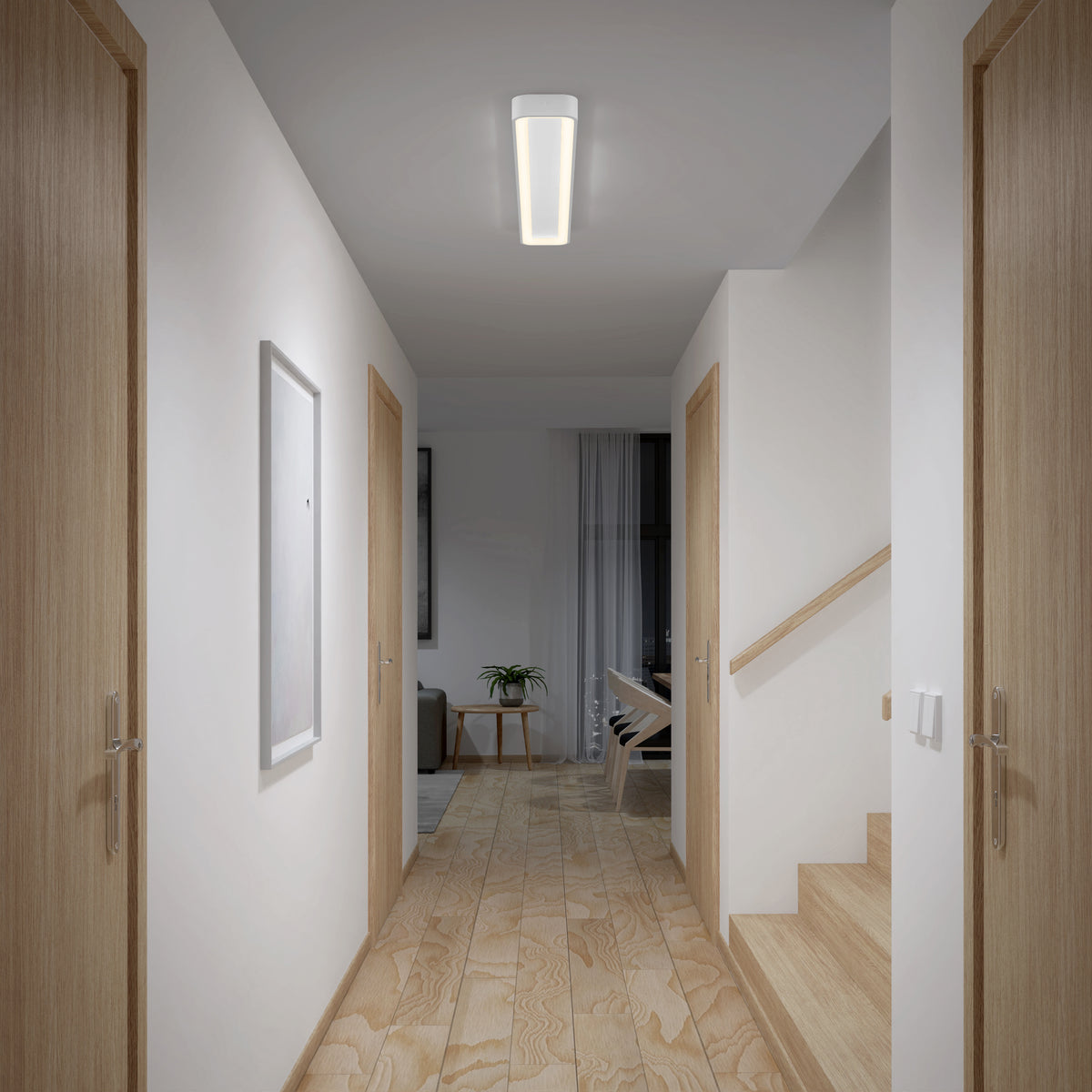 A modern hallway features light wood doors, stairs on the right, and a wooden floor. An Artika Aiden 48 in. LED modern flush mount light 5 CCT brightens the space. At the end is a room with a chair, table, plant, and sheer curtains.