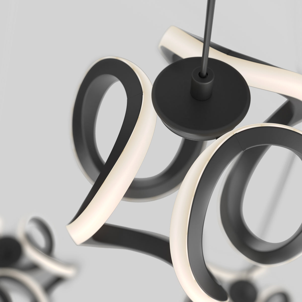 Close-up of a modern, abstract black and white LED pendant light fixture with curved, looped arms suspended from the ceiling against a plain, light gray background.
